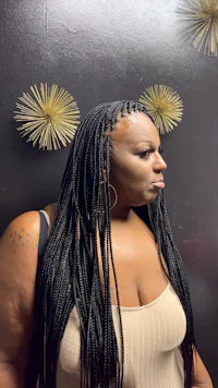 a woman with long braids standing in front of a wall