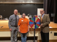 three people standing in front of a spinning wheel