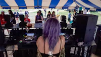 a woman with purple hair is djing at a festival