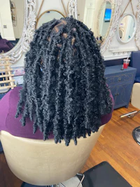 a woman sitting in a chair with black dreadlocks