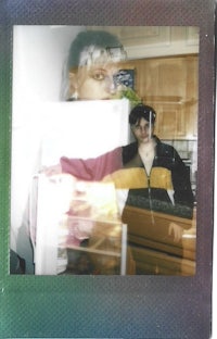 a polaroid photo of two people in a kitchen