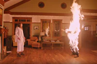 a man and woman standing in front of a fire in a living room