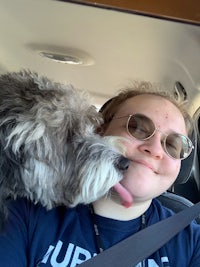 a woman is sitting in a car with her dog