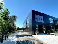 a black building with a walkway and trees