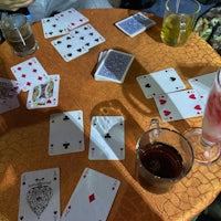 a group of people sitting around a table with playing cards