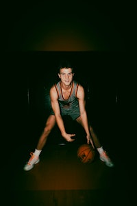 a young man posing with a basketball ball in the dark