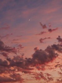 a sunset with clouds and a crescent in the sky