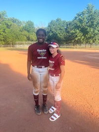 two softball players posing for a picture on a baseball field