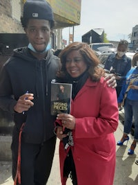 a man and woman standing next to each other holding a book