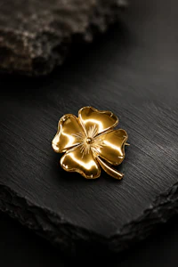 a gold leaf brooch on a black surface