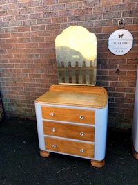a white dresser with a mirror next to a brick wall