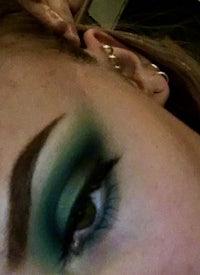 a woman with green eye makeup and piercings