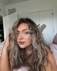a woman laying on a bed with long wavy hair