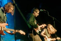 a group of people playing guitars on stage