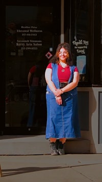 a woman in a denim dress standing outside of a store