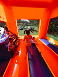 a group of children playing in an orange and blue bouncy castle