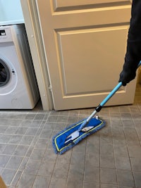 a person cleaning a tile floor with a mop