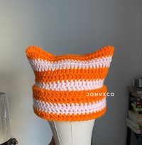 an orange and white crocheted cat hat on a mannequin