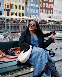 a woman is sitting on a bench in front of a building
