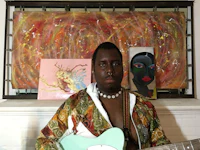 a man holding a guitar in front of a painting