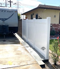 a white rv parked next to a white fence