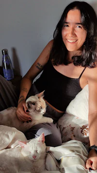 a woman laying on a bed with two cats