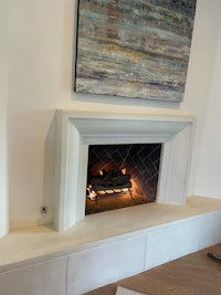 a fireplace in a living room with a painting on the wall