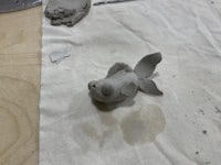 a clay fish sitting on a piece of paper