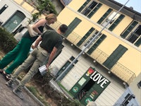 two people standing in front of a building with a sign that says love