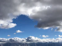 a cloudy sky with mountains in the background