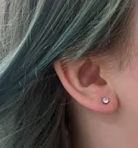 a girl with green hair and a piercing in her ear