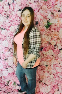 a woman posing in front of a pink flower wall