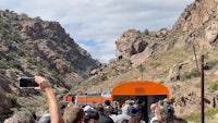 a crowd of people waiting to board a train in a canyon