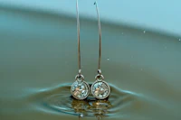 a pair of silver earrings sitting in water