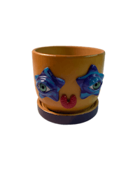 a yellow flower pot with blue eyes on it