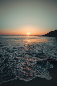a person standing on a beach at sunset