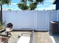 a backyard with a white fence and chairs