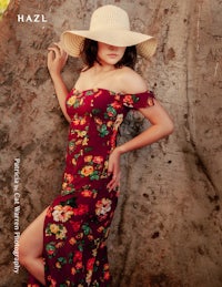 a woman in a floral dress leaning against a tree