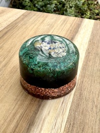 a green and black glass box on a wooden table