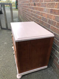 a pink chest of drawers sitting outside of a brick wall