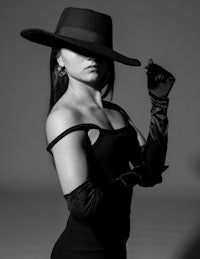 a woman in a black dress with a hat and gloves