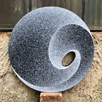a black and white yin yang sculpture on a stone wall