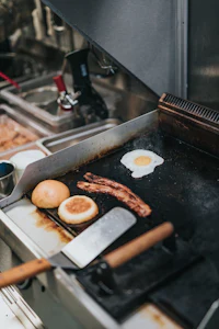 a griddle with bacon and eggs on it