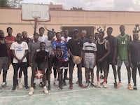 a group of young men posing for a picture on a basketball court