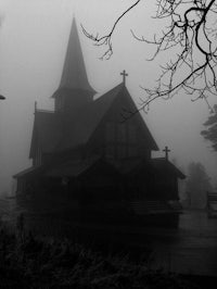 a black and white photo of a church in the fog