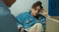 a woman in a denim jacket sitting next to a box