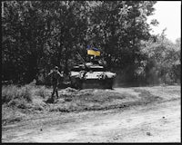 an old black and white photo of a tank on a dirt road