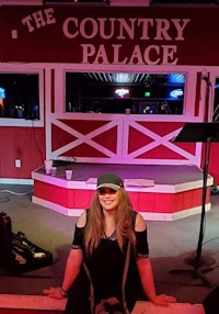 a woman sitting in front of a stage at the country palace