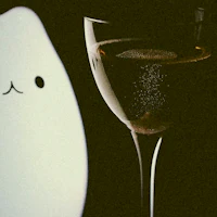 a white cat sitting next to a glass of wine