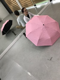 a woman holding a pink umbrella in front of a mirror